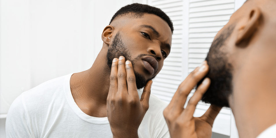 A black man checking his face for razor bumps.